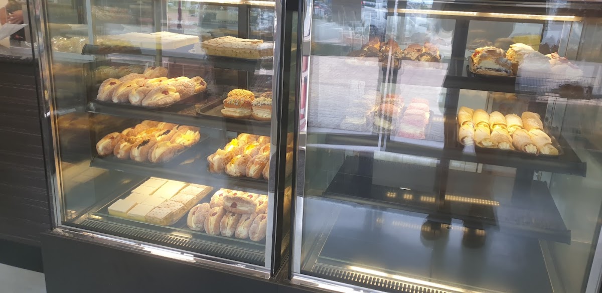 A cabinet full of cream buns, custard squares and danishes at Beresford Bakery